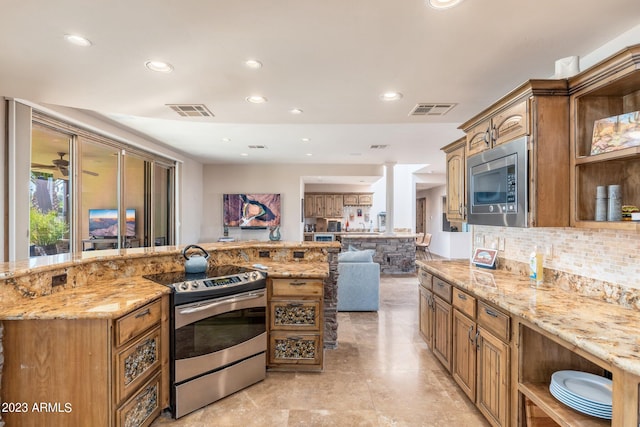 kitchen featuring tasteful backsplash, decorative columns, appliances with stainless steel finishes, and light stone counters