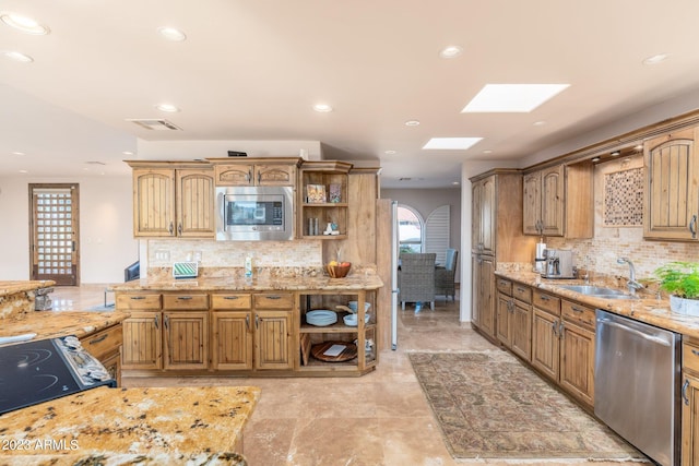 kitchen featuring appliances with stainless steel finishes, light stone counters, decorative backsplash, and sink