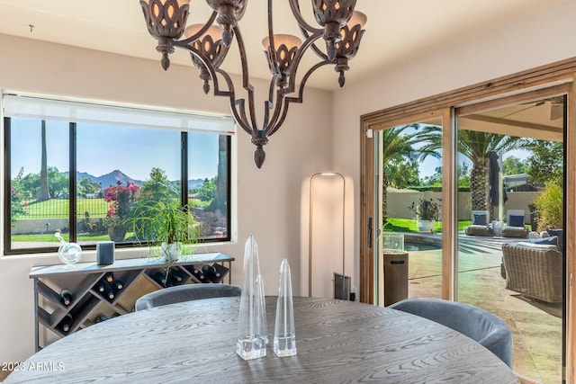 dining room featuring a healthy amount of sunlight, a mountain view, and an inviting chandelier