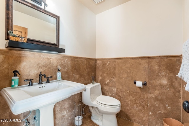 bathroom with tile walls, sink, and toilet