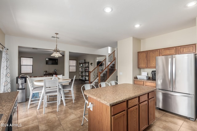 kitchen featuring pendant lighting, light tile patterned floors, a kitchen island, stainless steel appliances, and a kitchen bar