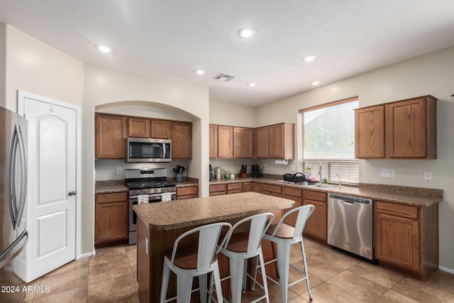 kitchen with light tile patterned floors, a breakfast bar area, a center island, and stainless steel appliances