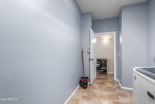 hallway with light tile patterned flooring and washer / dryer