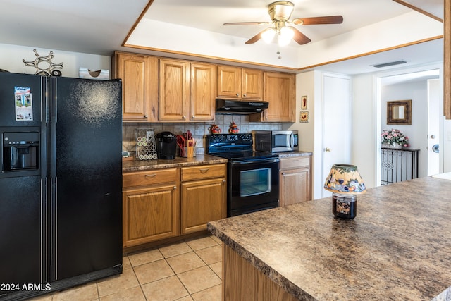 kitchen featuring ceiling fan, backsplash, a tray ceiling, light tile patterned floors, and black appliances