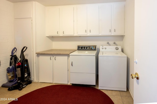 laundry room with washing machine and clothes dryer, light tile patterned floors, and cabinets