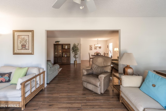 living room featuring ceiling fan with notable chandelier, dark hardwood / wood-style flooring, and a textured ceiling