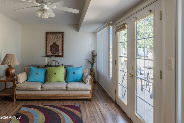 living room with a textured ceiling, ceiling fan, dark wood-type flooring, and french doors