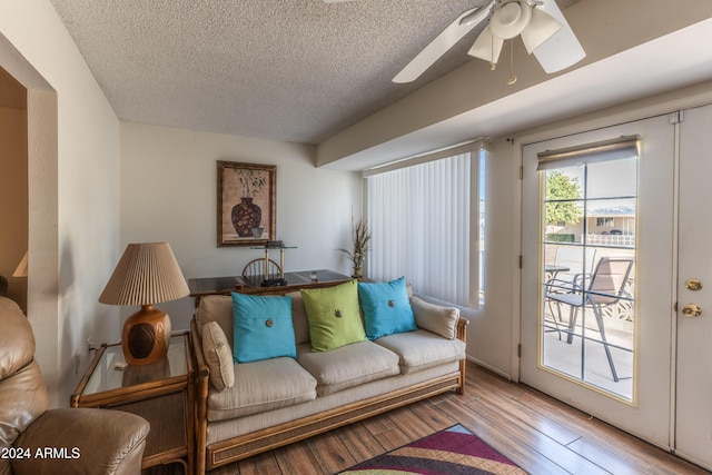 living room with hardwood / wood-style floors, ceiling fan, and a textured ceiling