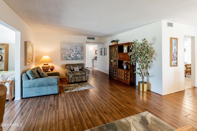 living room featuring a textured ceiling and dark wood-type flooring