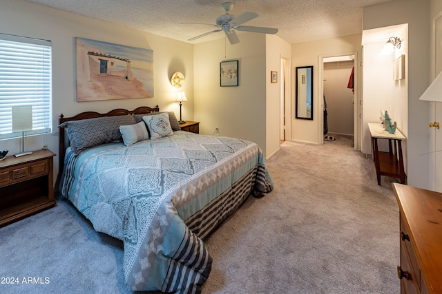 carpeted bedroom featuring a walk in closet, ceiling fan, a closet, and a textured ceiling