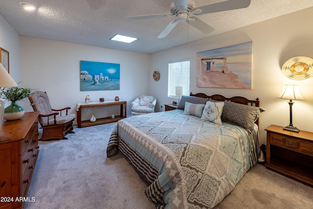 carpeted bedroom featuring ceiling fan, a textured ceiling, and a skylight