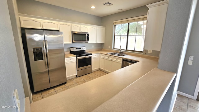 kitchen with white cabinets, light tile patterned floors, appliances with stainless steel finishes, and sink