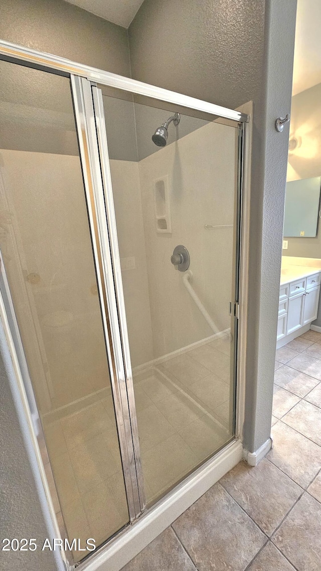 bathroom with walk in shower, vanity, and tile patterned flooring