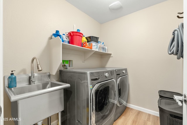 laundry area with washer and dryer, sink, and light hardwood / wood-style flooring