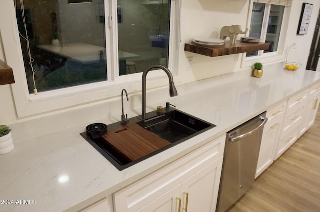 kitchen with light stone counters, white cabinets, sink, light hardwood / wood-style flooring, and dishwasher