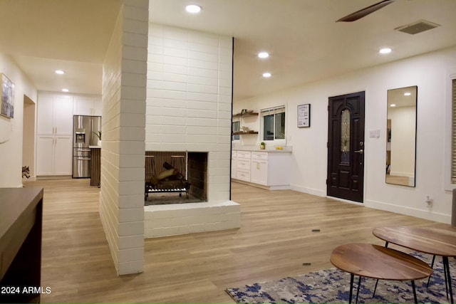 living room featuring light wood-type flooring and a fireplace