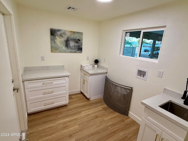 clothes washing area with light hardwood / wood-style floors, cabinets, hookup for a washing machine, and sink