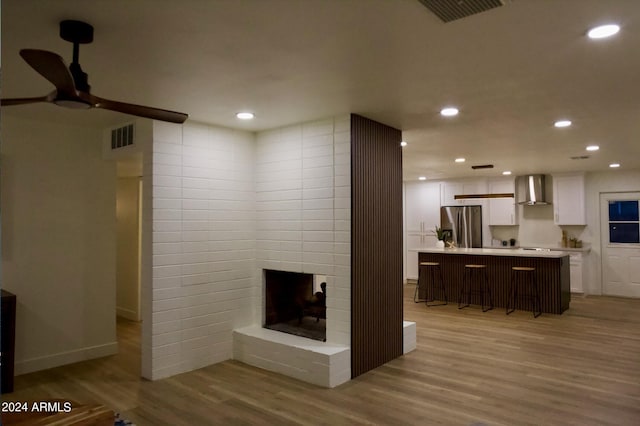 living room featuring a brick fireplace, light hardwood / wood-style flooring, and ceiling fan