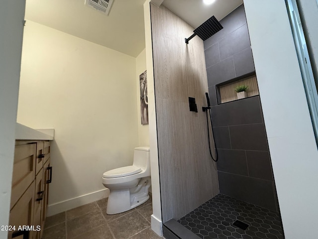 bathroom featuring a tile shower, tile patterned floors, vanity, and toilet