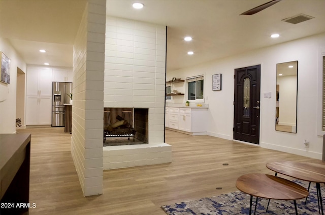 living room with a brick fireplace and light hardwood / wood-style flooring