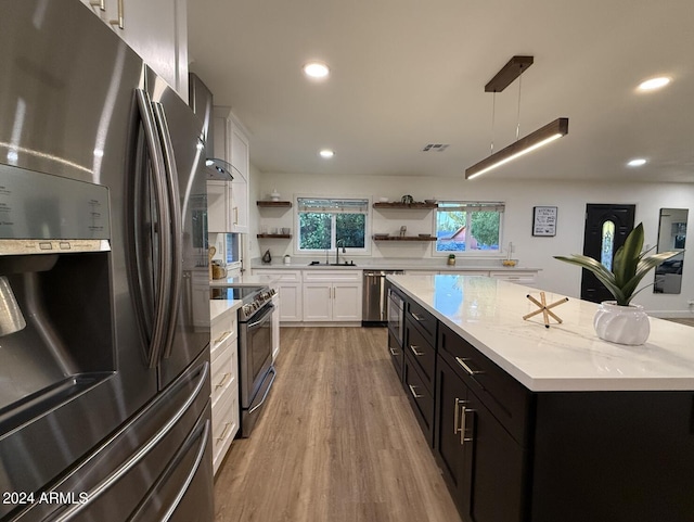 kitchen featuring a center island, stainless steel appliances, sink, hanging light fixtures, and white cabinetry