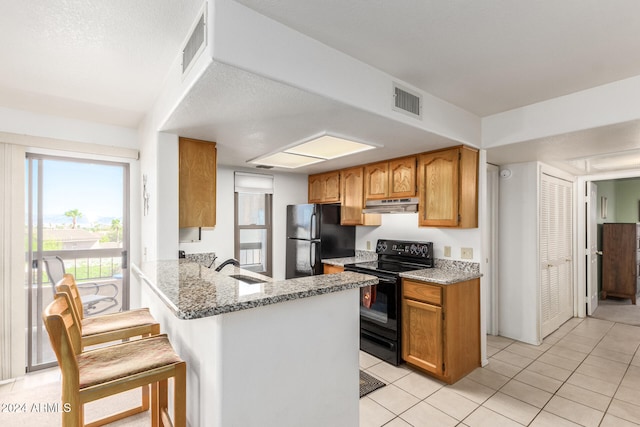 kitchen with light stone counters, black appliances, kitchen peninsula, and a kitchen breakfast bar