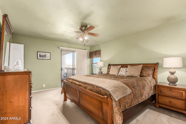 bedroom with a textured ceiling, light colored carpet, and ceiling fan