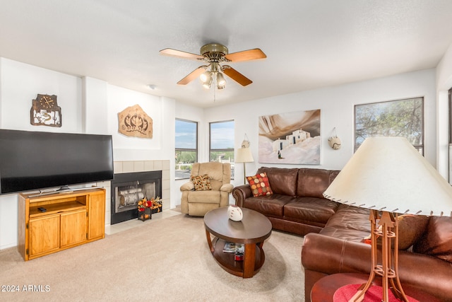 carpeted living room with a tiled fireplace and ceiling fan