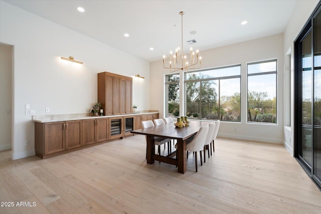 dining area featuring an inviting chandelier, plenty of natural light, beverage cooler, and light hardwood / wood-style flooring