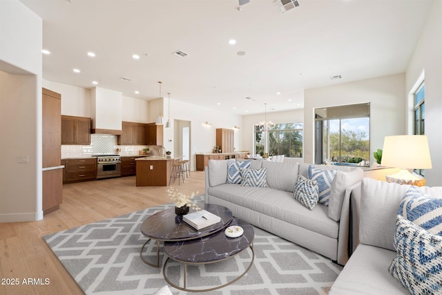 living room with sink, a notable chandelier, and light wood-type flooring