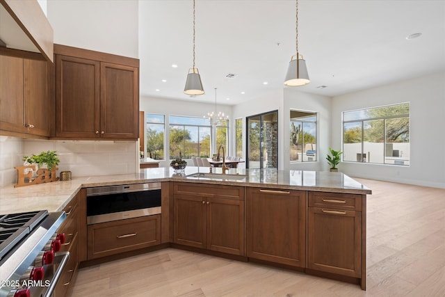 kitchen with pendant lighting, sink, a wealth of natural light, and light wood-type flooring