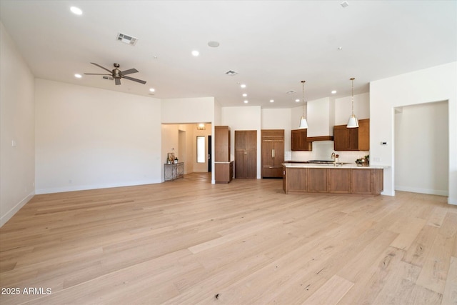 unfurnished living room featuring ceiling fan, sink, and light hardwood / wood-style floors