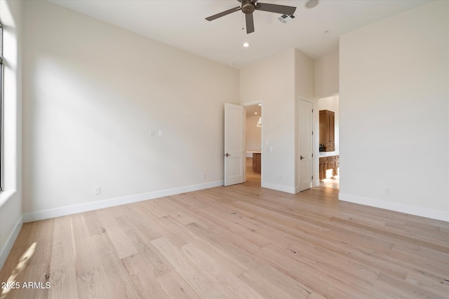 empty room with ceiling fan and light hardwood / wood-style flooring