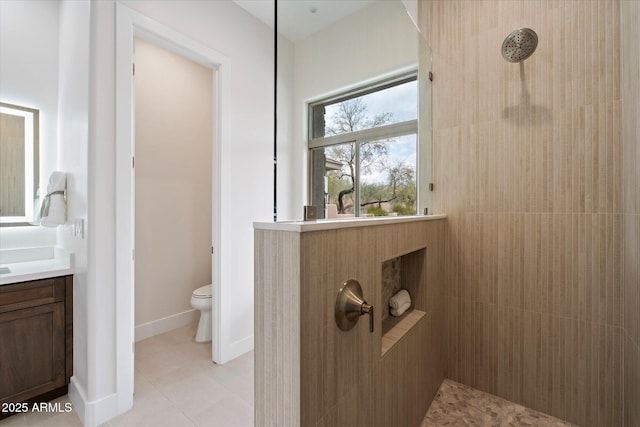 bathroom with vanity, tile patterned flooring, toilet, and tiled shower