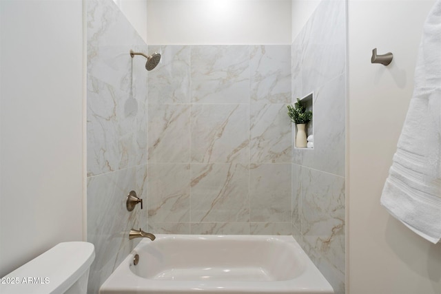 bathroom with tiled shower / bath combo and toilet