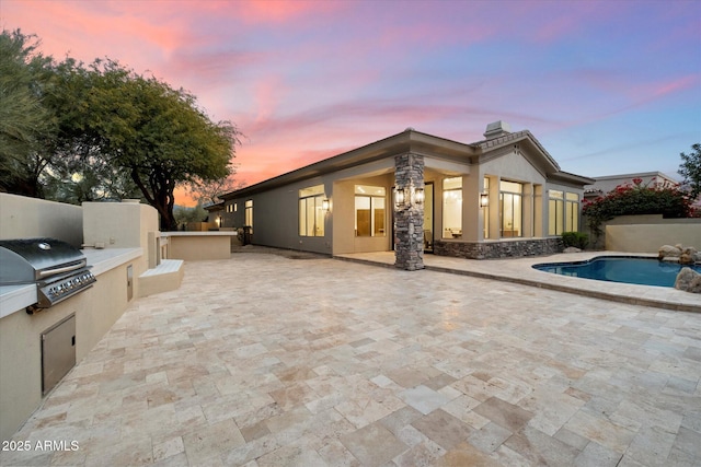 back house at dusk featuring area for grilling, a fenced in pool, and a patio