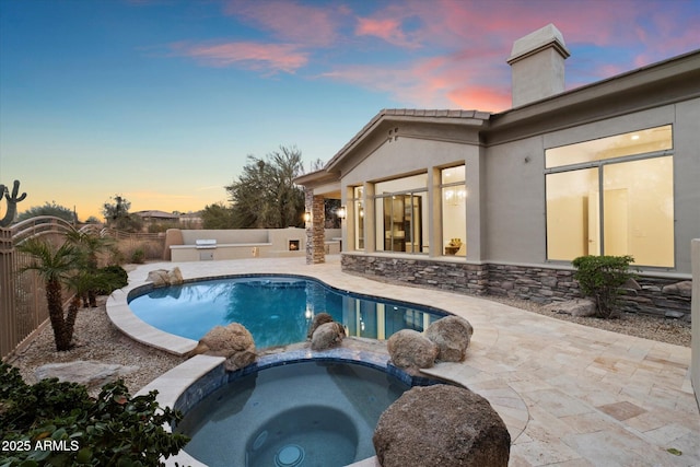 pool at dusk featuring an in ground hot tub and a patio