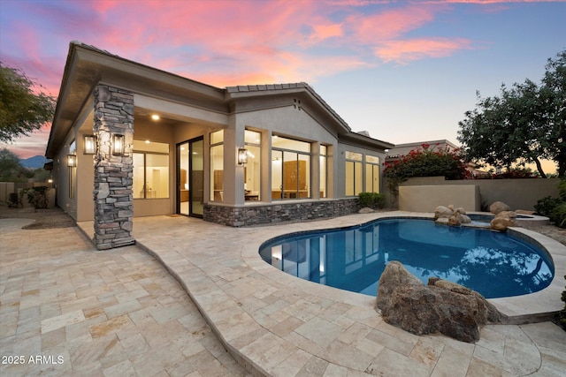 pool at dusk featuring a patio