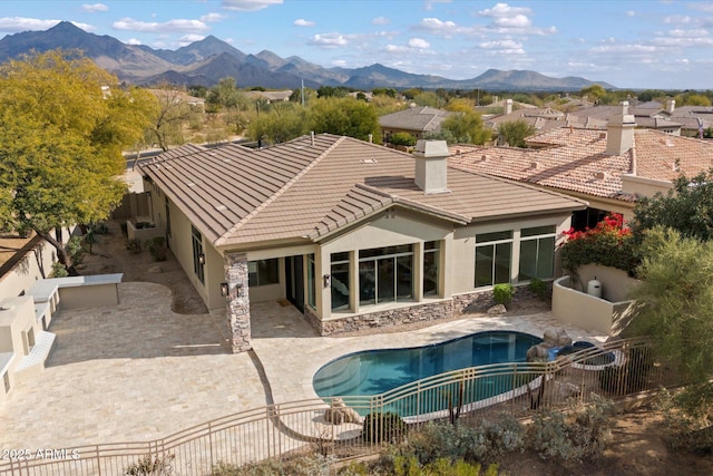 rear view of house featuring a fenced in pool, a mountain view, and a patio