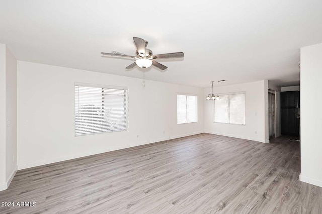 empty room featuring light hardwood / wood-style floors and ceiling fan with notable chandelier