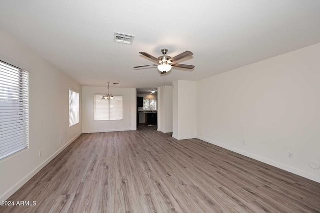 unfurnished living room featuring wood-type flooring and ceiling fan with notable chandelier