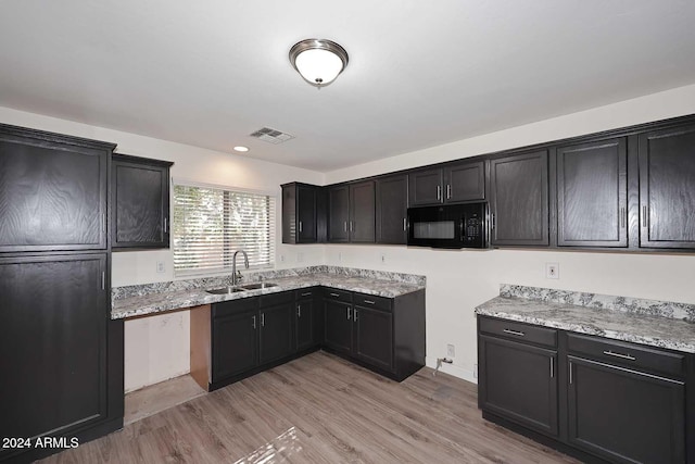 kitchen with light stone counters, sink, and light wood-type flooring