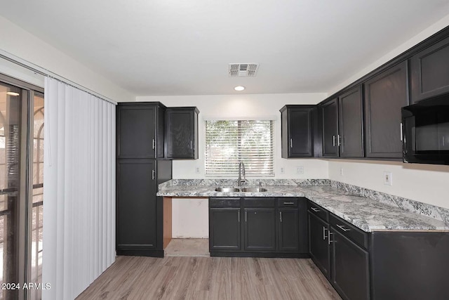 kitchen featuring light stone countertops, sink, and light wood-type flooring