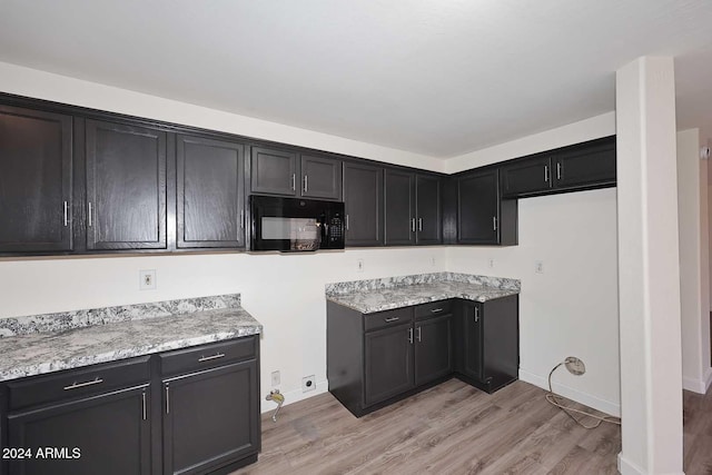 kitchen featuring light stone countertops and light wood-type flooring