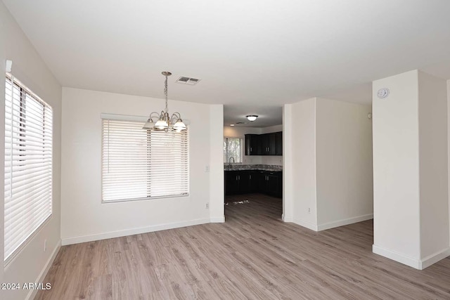 unfurnished dining area featuring sink, hardwood / wood-style floors, and an inviting chandelier