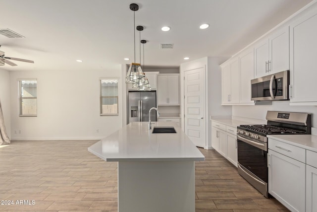 kitchen with pendant lighting, a kitchen island with sink, sink, appliances with stainless steel finishes, and white cabinetry