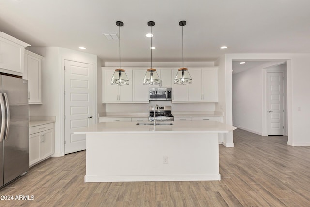 kitchen with sink, stainless steel appliances, an island with sink, pendant lighting, and light wood-type flooring