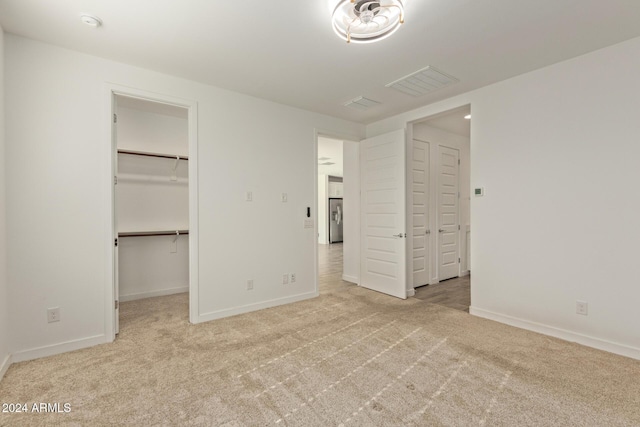 unfurnished bedroom featuring light carpet, a spacious closet, and a closet