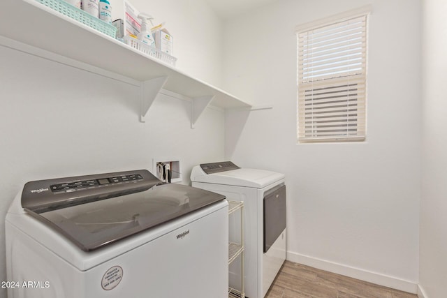 clothes washing area featuring washer and clothes dryer and light hardwood / wood-style flooring