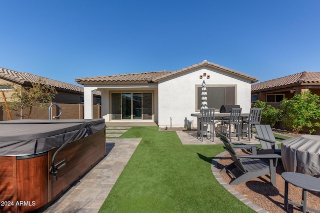 rear view of house with a lawn, a patio, and a hot tub